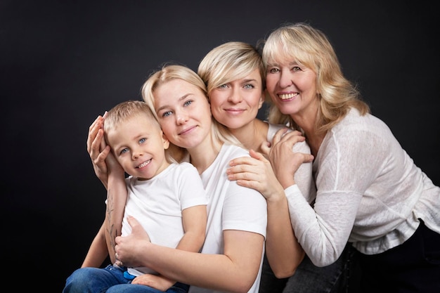 Retrato de tres generaciones de mujeres y un niño Abuela madre hija e hijo en camisetas blancas Amor y ternura Fondo negro