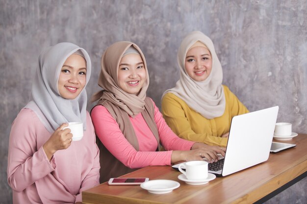 Retrato de tres hermosa mujer musulmana trabajando juntos en su computadora portátil en la cafetería
