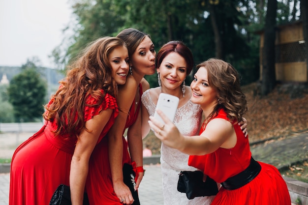 Retrato de tres hermosas damas de honor en vestido rojo