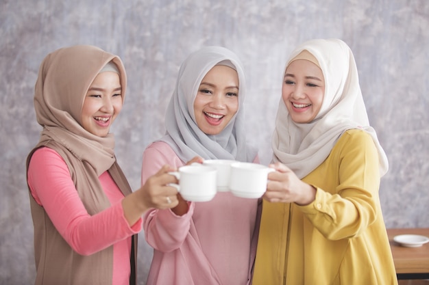 Retrato de tres hermosas mujeres musulmanas anima a su café después de lograr un gran trabajo y éxito