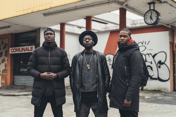 Foto retrato de tres jóvenes africanos posando al aire libre en la calle