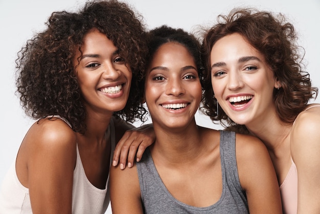 Retrato de tres jóvenes mujeres multirraciales de pie juntos y sonriendo a la cámara