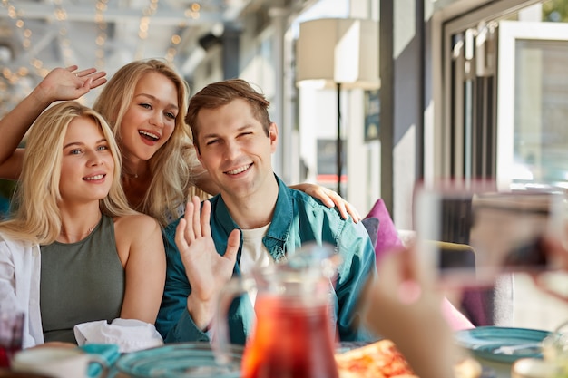 Retrato de tres mejores amigos jóvenes sentados en el café