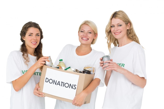 Retrato de tres mujeres jóvenes sonrientes con caja de donación