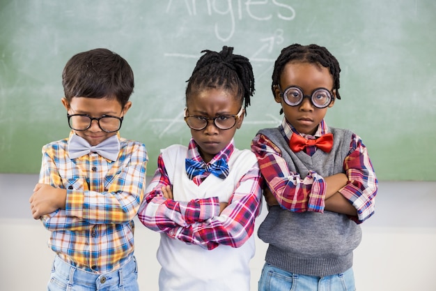 Retrato de tres niños de la escuela de pie contra la pizarra