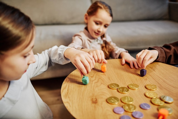 Retrato de tres niños jugando al tradicional juego de dreidel en un acogedor espacio de copia de iluminación cálida