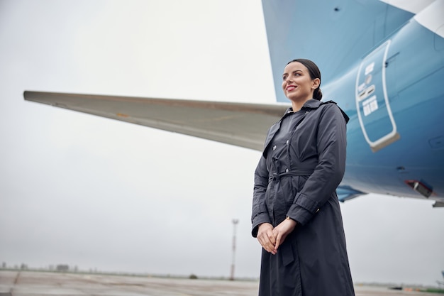 Retrato de la tripulación del avión caucásico seguro feliz cerca del avión