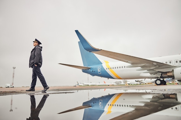 Retrato de la tripulación del avión caucásico seguro feliz cerca del avión