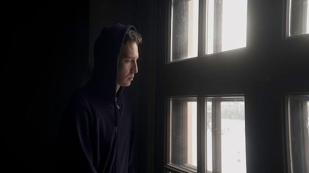 Foto retrato triste de um homem de ação um jovem bonito olhando pela janela dentro de casa com um pensativo