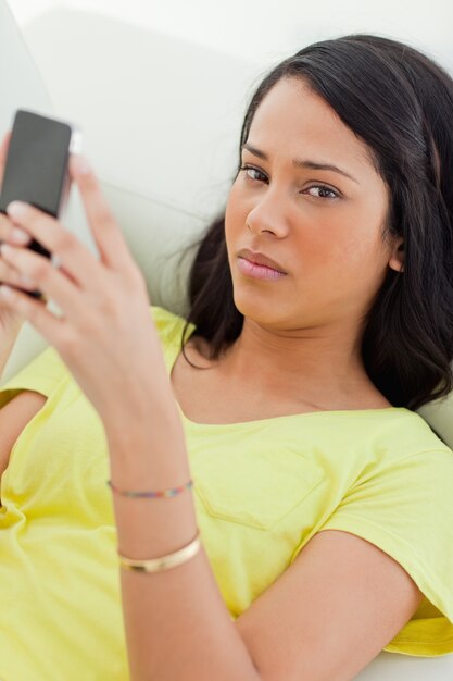 Retrato de un triste latino sosteniendo su teléfono inteligente