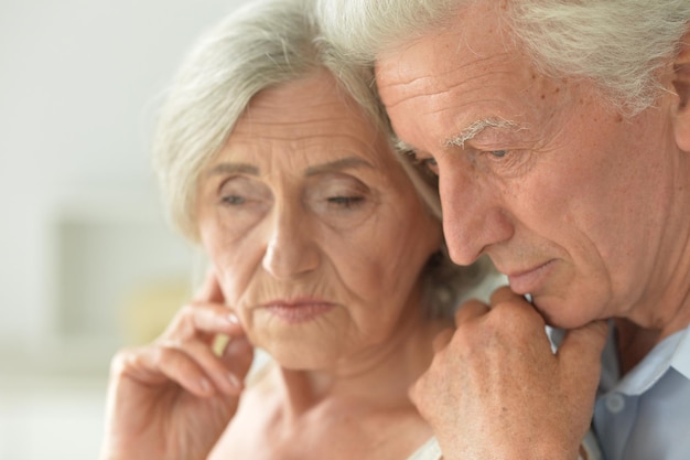 Retrato de una triste pareja de ancianos posando en casa