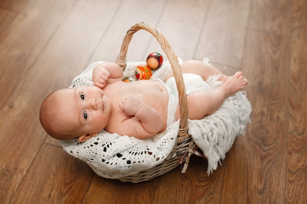 Retrato um bebê bonito na cesta de vime easter. bebê recém-nascido na cesta de vime na parede de madeira. criança sorridente e ovos de páscoa