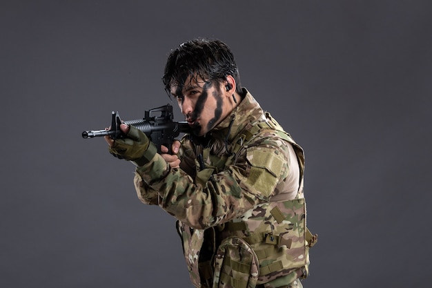 Retrato de valiente soldado en camuflaje durante la operación en la pared oscura