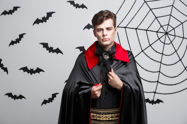 Retrato del vampiro caucásico hermoso en el traje negro y rojo de Halloween.