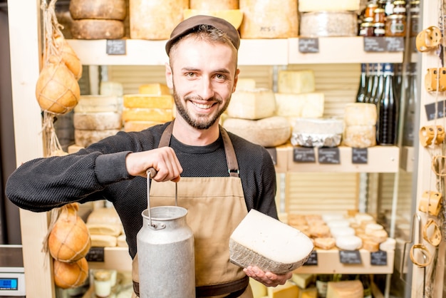 Retrato de un vendedor de queso con gran cuchara de productos lácteos de pie en la tienda de quesos