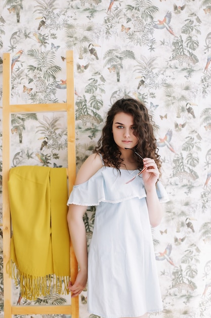 Retrato de verano de una hermosa chica romántica con un vestido en el interior