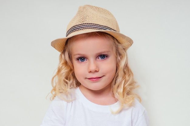 Retrato de verano de una niña rubia en una red de captura de mariposas de sombrero de paja sobre un fondo blanco en el estudio.Muy turista viajando.