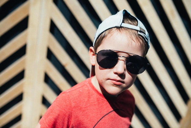 Retrato de verano de un niño con gafas de sol y una gorra de béisbol