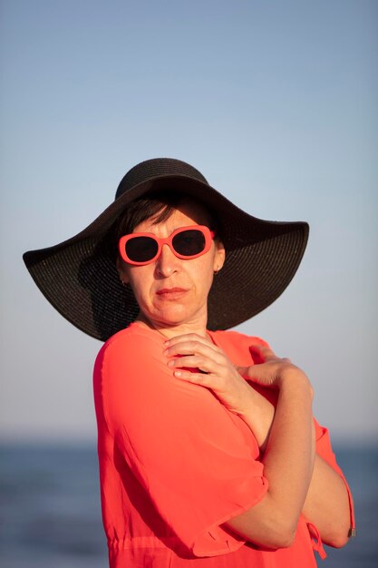 Retrato vertical de una anciana en un sombrero sobre un fondo del mar