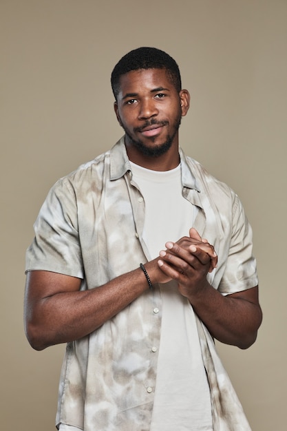 Retrato vertical de homem afro-americano bonito, vestindo camisa e olhando para a câmera enquanto posava ...