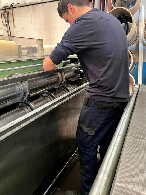 Retrato vertical de um homem colocando as lâminas para cortar chapas metálicas em uma indústria metalúrgica de máquinas de corte de metal