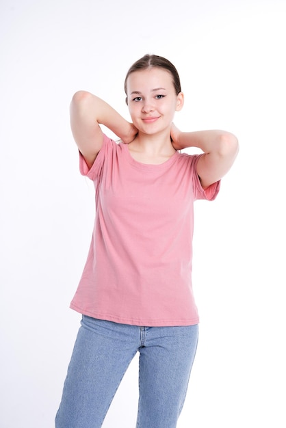 Retrato vertical de uma linda jovem de camiseta rosa isolada em modelo de fundo branco posando