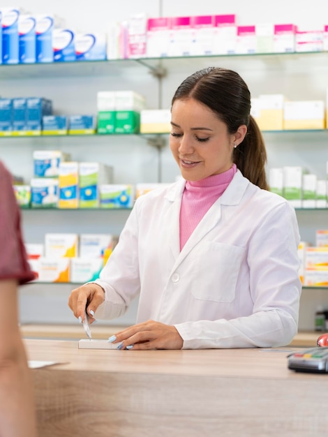 Retrato vertical de una farmacéutica cortando el código de barras de un medicamento recetado