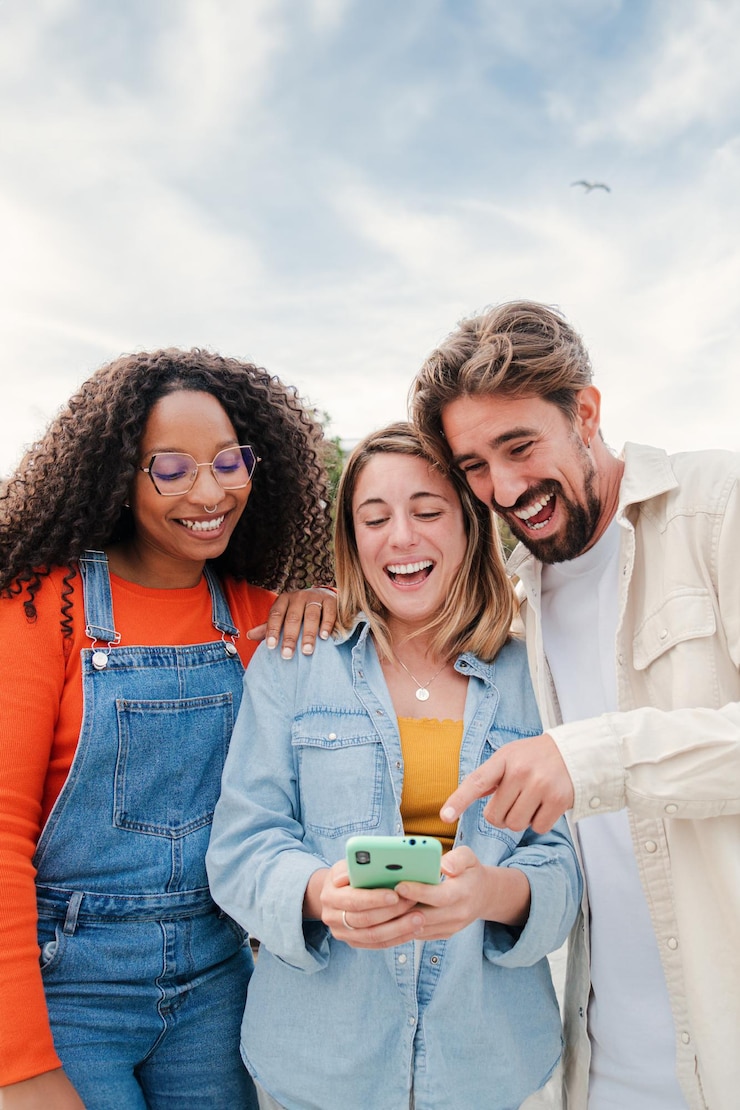 Foto retrato vertical de un grupo de amigos divirtiéndose con un teléfono móvil viendo videos divertidos en las redes sociales