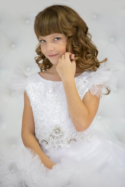 Retrato vertical de una hermosa chica con lokans en un vestido blanco.