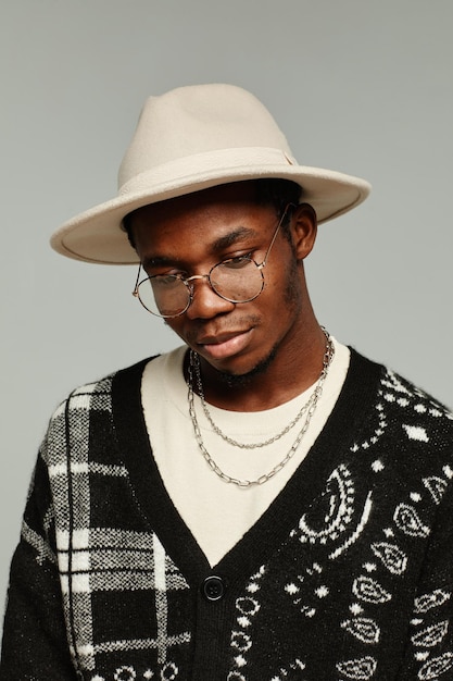 Retrato vertical del hombre afroamericano en estilo con sombrero contra el fondo gris