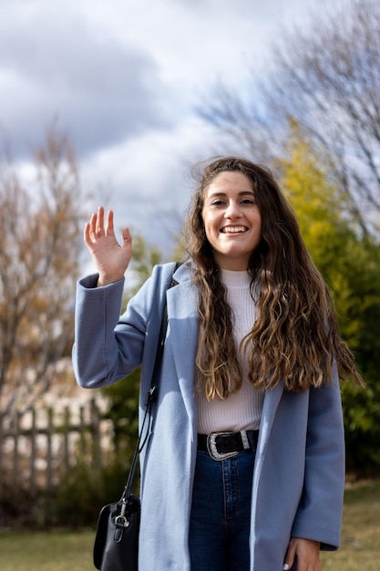 Retrato vertical de una joven caucásica sonriente que agita la pantalla de videollamada