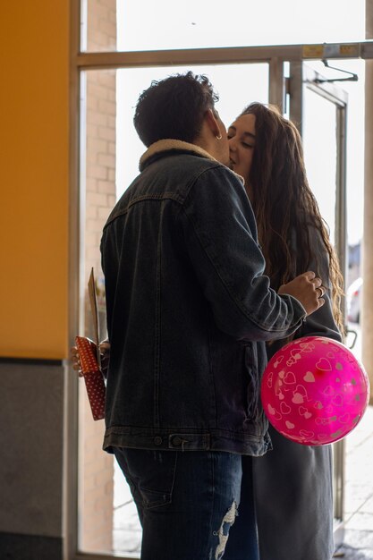 Retrato vertical de un joven latino besando y abrazando a su novia agradeciéndole la sorpresa del Día de San Valentín. celebración del día de San Valentín.