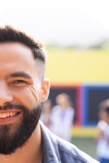 Retrato vertical de media cara de un profesor de escuela masculino caucásico barbudo y sonriente al aire libre, espacio de copia