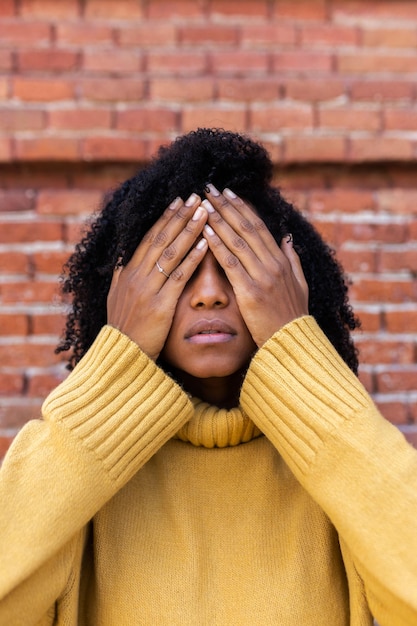 Retrato vertical de una mujer afroamericana que cubre los ojos con las manos Concepto de miedo