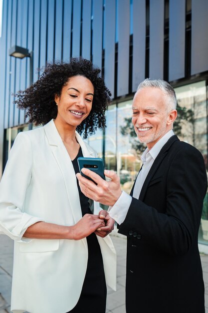 Retrato vertical de personas de negocios que usan un teléfono celular para ver las acciones de las acciones que muestra el empresario