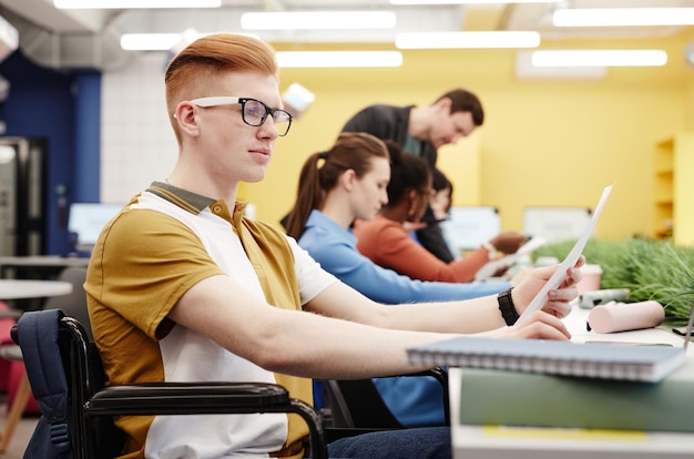 Retrato vibrante da vista lateral de um jovem ruivo com deficiência estudando no espaço de cópia da faculdade