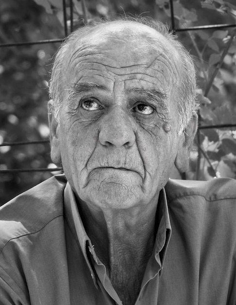 Retrato de un viejo jubilado griego serio con una sonrisa en color blanco y negro