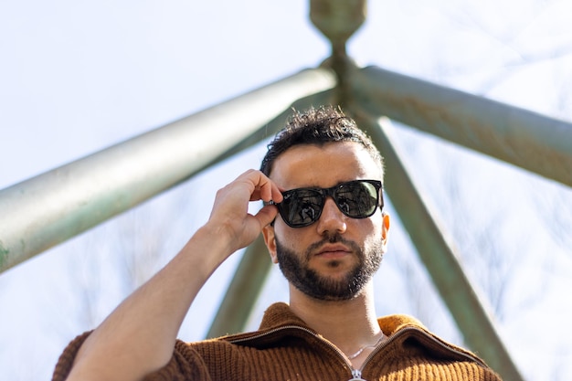 Foto retrato de vista inferior de un joven barbudo poniéndose gafas de sol listas para el verano