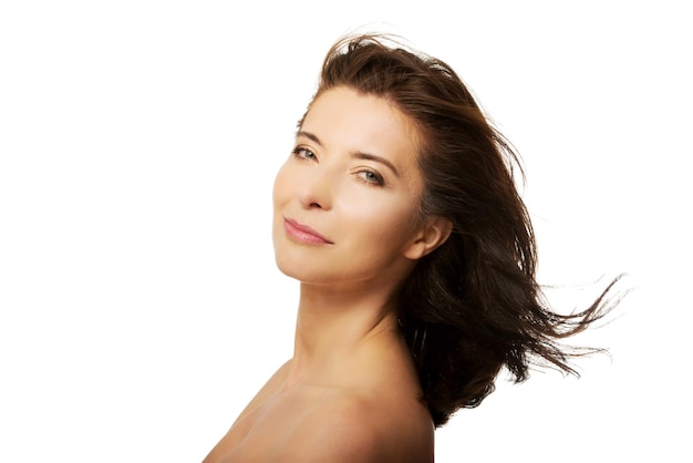 Retrato de vista lateral de una mujer sin camisa sonriendo contra un fondo blanco