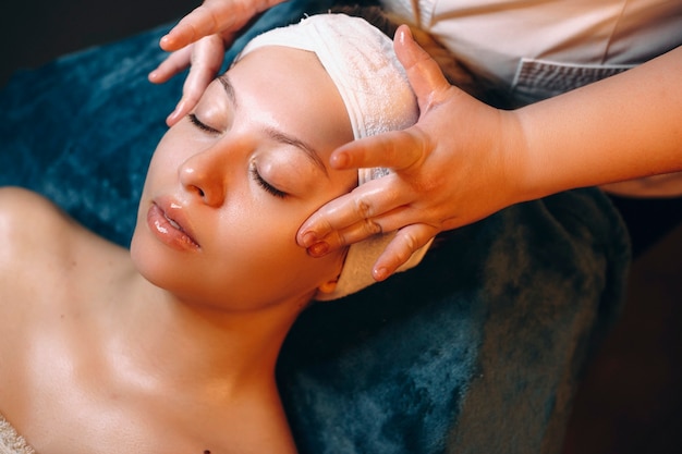 Retrato de vista lateral de una mujer joven con una rutina de cuidado de la piel en un centro de spa.