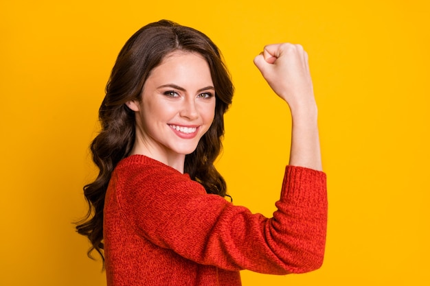 Retrato de vista lateral de perfil de primer plano de ella ella bonita contenido atractivo atractivo alegre alegre chica de pelo ondulado que muestra un brazo fuerte aislado sobre fondo de color amarillo vibrante de brillo vivo brillante