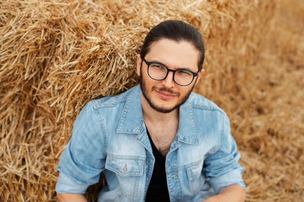 Retrato de vista superior de joven sonriente sentado cerca de un pajar.