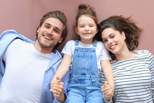 Foto retrato de vista superior de padres jóvenes sonrientes con hija de niño en edad preescolar acostado relajándose en un piso cálido en casa, familia feliz con descanso de niño pequeño divertirse en casa.