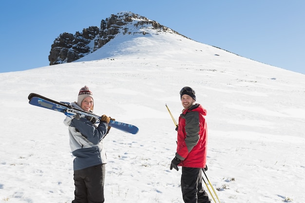 Retrato de vista trasera de una pareja sonriente con tablas de esquí en la nieve