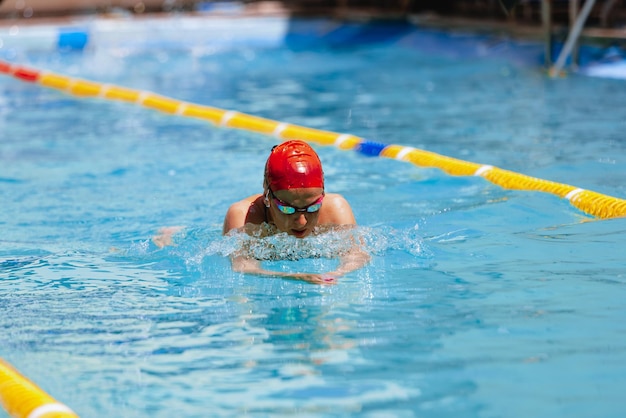 Retrato en vivo de una joven nadadora con gorro de natación y practicando en una piscina pública al aire libre