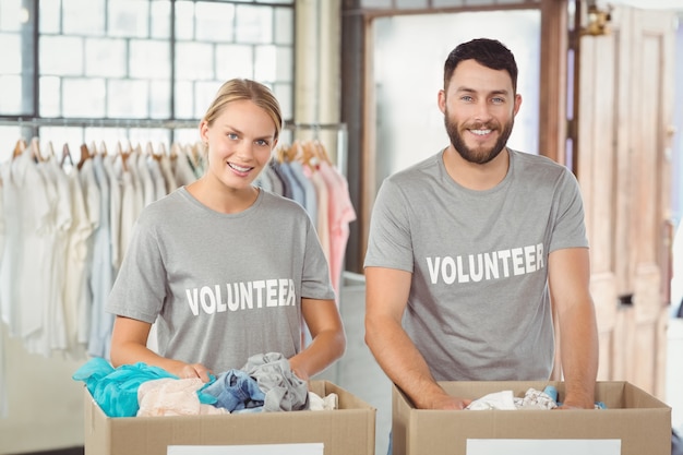 Foto retrato de voluntarios sonrientes separando donaciones ropa
