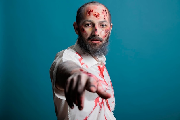 Retrato de zombi de Halloween posando en la cámara, luciendo espeluznante y peligroso con cicatrices apocalípticas y heridas sangrientas en el estudio. Monstruo malvado y agresivo que come cerebros, cadáver aterrador.