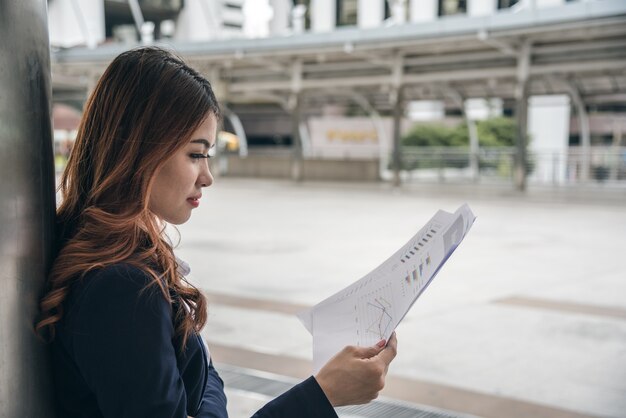 Retratos de mulher asiática bonita na expressão de pensamento trabalhando com gráfico financeiro