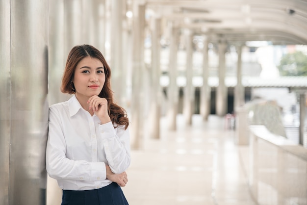 Retratos de mulher asiática bonita parecem alegres e a confiança está em pé ao ar livre