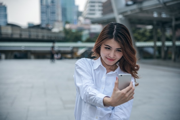 Retratos de Pretty Beautiful Asian woman tomando uma foto por selfie em urbano.